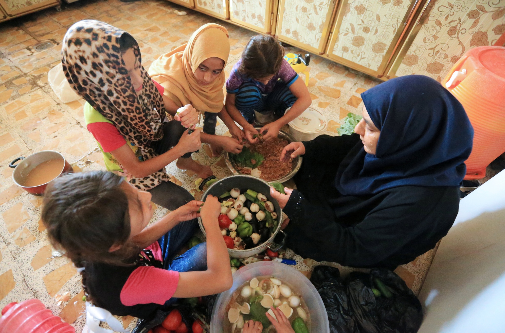 An Iraqi woman Sana Ibrahim al-Taee, 64, whose five sons were killed by Islamic State militants, prepares food with grandchildren at her home in Mosul, Iraq July 30, 2018. Picture taken July 30, 2018. REUTERS/Ari Jalal