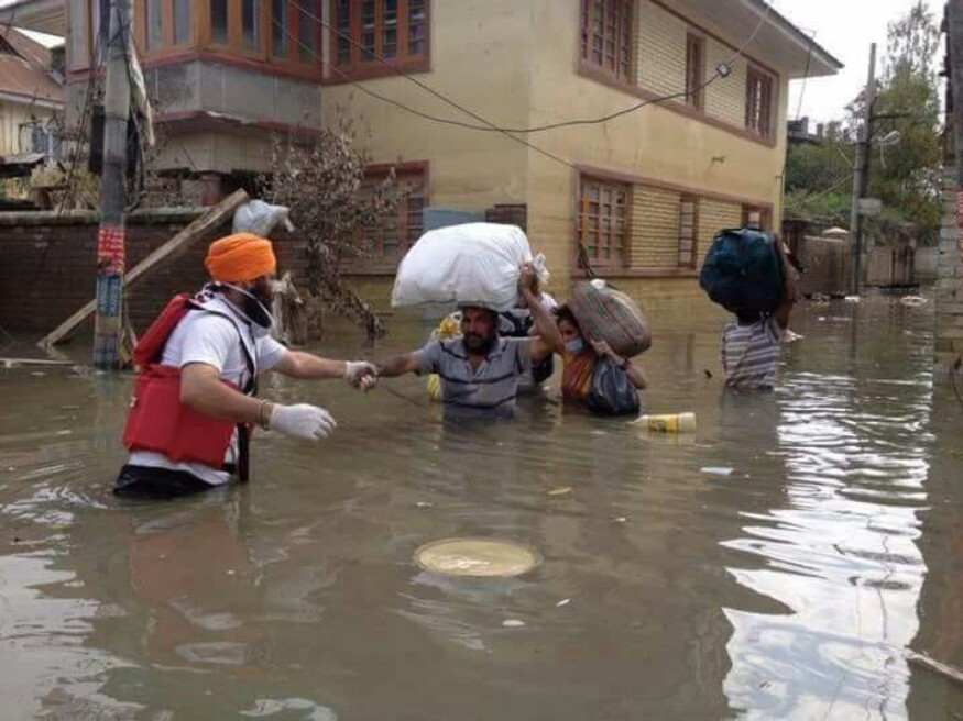 Volunteers of Khalsa Aid assembling essential commodities food for flood-affected victims in chest-deep water. (Image: News18/ Pankaj Tomar)