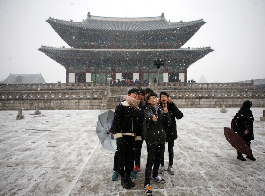 Students take a 'selfie' during snowfall in winter at Gyeongbok Palace in central Seoul. (Image: Reuters)