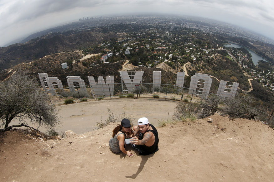 A couple poses for a selfie behind the Hollywood sign in Los Angeles, California. (Image: Reuters)