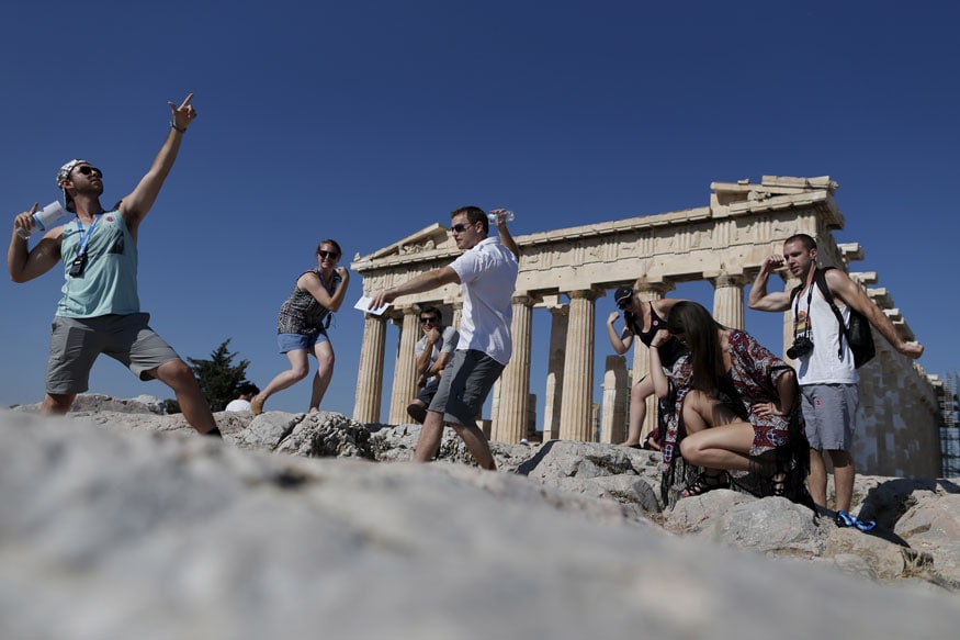 A group of tourists takes a selfie in front of the temple of the Parthenon atop the Acropolis in Athens, Greece. (Image: Reuters)