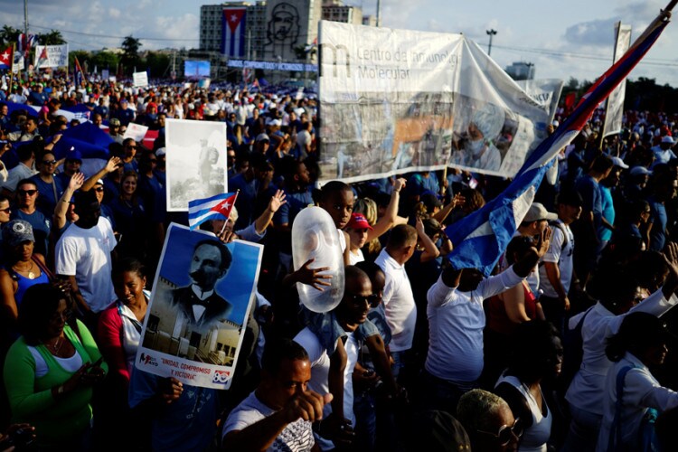 Child carries an inflated condom during the May Day rally in Havana