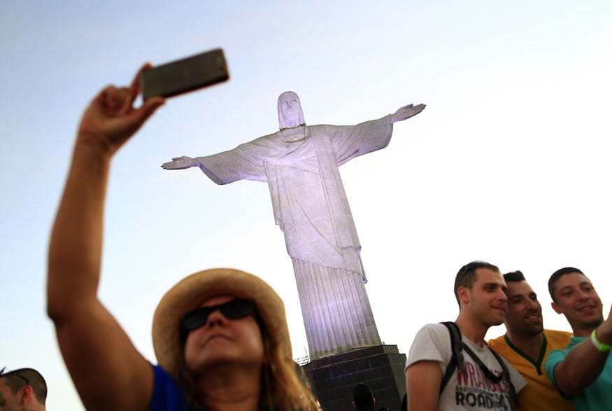 A woman poses for a selfie in front of the statue of Christ the Redeemer in Rio de Janeiro. (Image: Reuters)