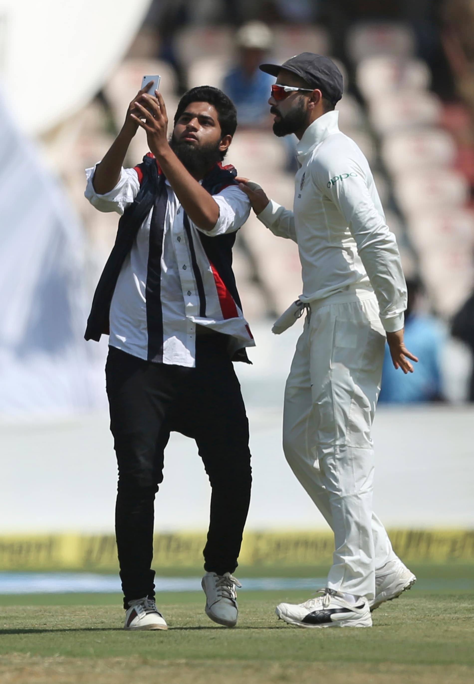 An Indian fan takes a selfie with cricketer Virat Kohli after running into the field disrupting the first day of the second cricket test match between India and West Indies in Hyderabad, India, Friday, Oct. 12, 2018. (AP Photo/Mahesh Kumar A.)