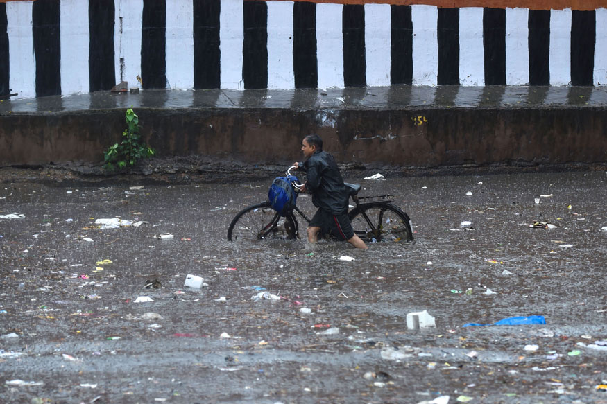 A cyclist wades through a flooded road near Kashmiri Gate during a heavy downpour, in New Delhi. (Image: PTI)