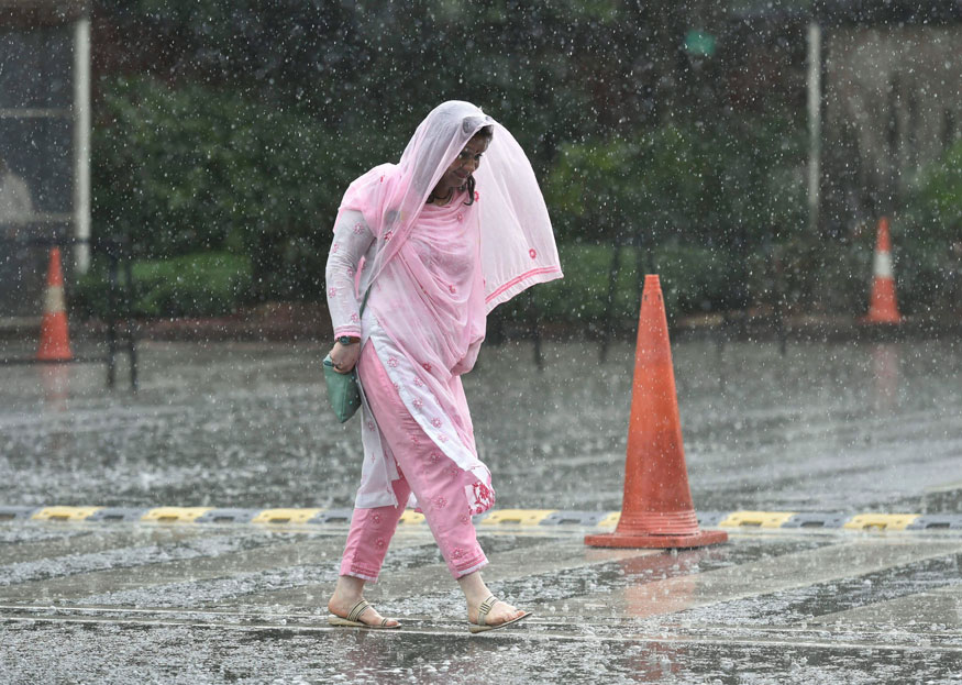 A woman crosses a road during Monsoon rain, in New Delhi. (Image: PTI)