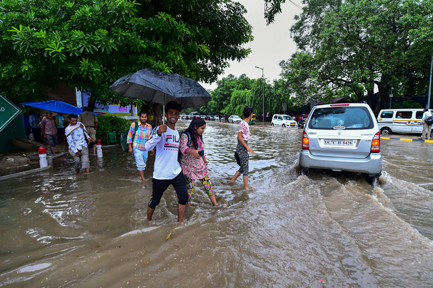 Pedestrians cross a flooged street after heavy monsoon rain, in New Delhi. (Image: PTI)
