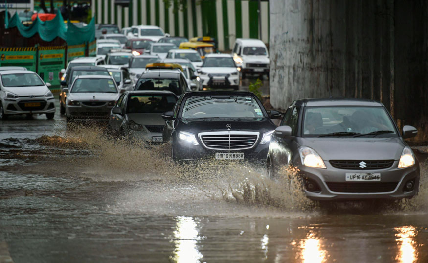 Vehicles ply at a flooded road after a downpour in New Delhi. (Image: PTI)