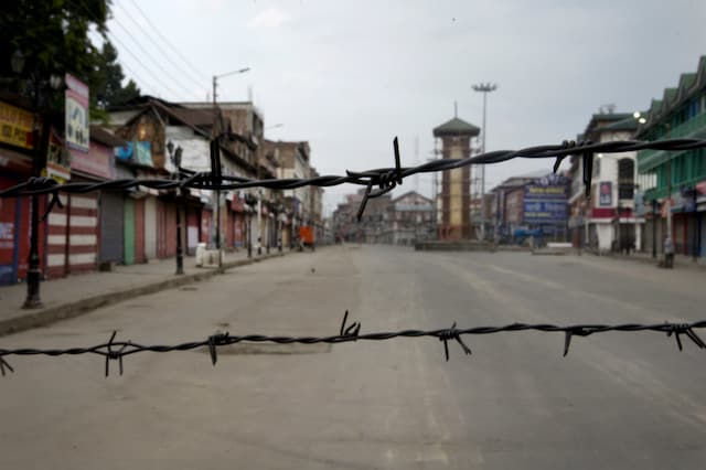 In this August 6, 2019 file photo, a deserted street is seen through a barbwire set up as blockade during curfew in Srinagar. (AP)