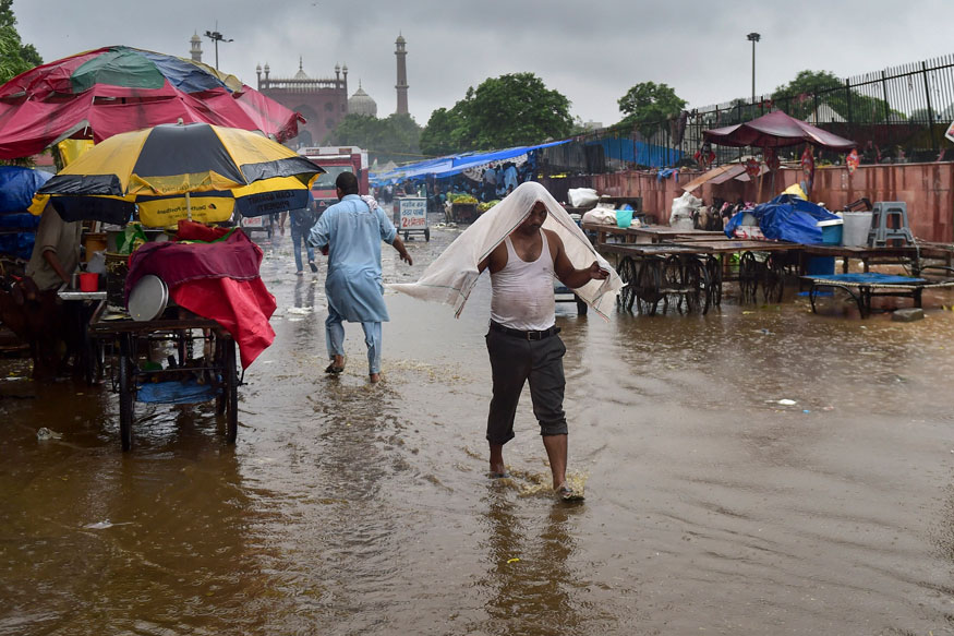 A man tries to protect himself as its rains, near Jama Masjid, New Delhi. (Image: PTI)