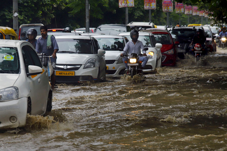 Vehicles wade through a waterlogged road during rains, in Gurugram. (Image: PTI)