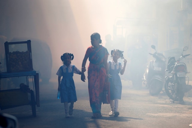 A woman and her two daughters cross a road after a health worker fumigates a residential area. (Image for representation)