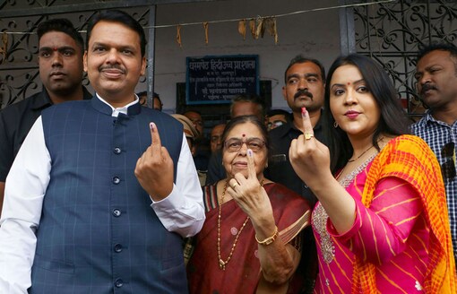 Maharashtra Chief Minister Devendra Fadnavis, wife Amruta and mother Sarita show their finger marked with indelible ink after casting vote during Maharashtra Assembly elections, in Nagpur district of Maharashtra. (Image: PTI)