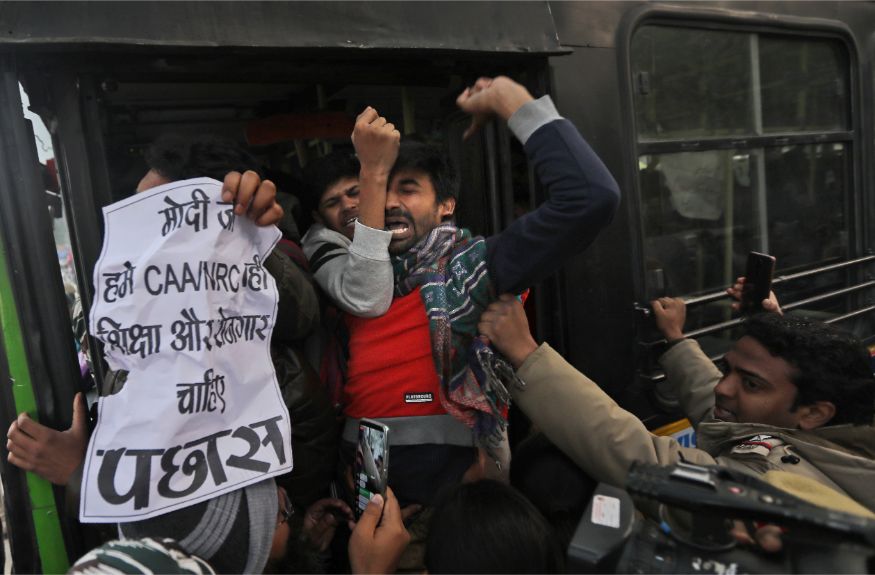 Policemen push students into a bus after they are detained during a protest outside Uttar Pradesh Bhawan against a new citizenship law and violence by police in the state, in New Delhi. (Image: AP)