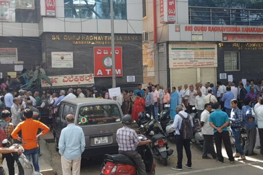 Depositors wait outside a branch of the bank on Tuesday. (News18) Depositors wait outside a branch of the bank on Tuesday. (News18)