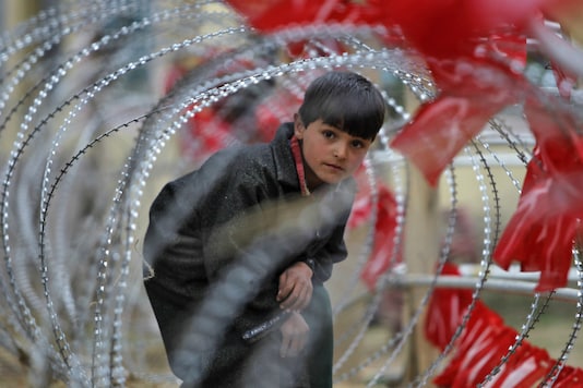 File photo of a Kashmiri boy looking through a concertina wire barricade set up by the police in Pulwama. (Reuters/Photo for representation only) File photo of a Kashmiri boy looking through a concertina wire barricade set up by the police in Pulwama. (Reuters/Photo for representation only)