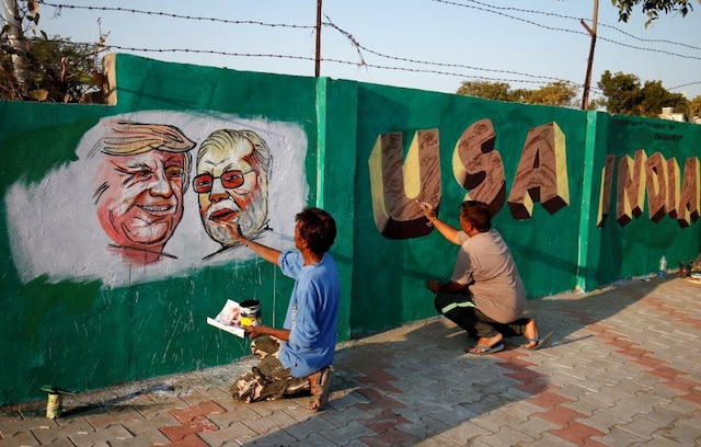 A man applies finishing touches to paintings of US President Donald Trump and Prime Minister Narendra Modi on a wall as part of a beautification along a route that Trump and Modi will be taking during Trump's upcoming visit, in Ahmedabad. (Image: Reuters)