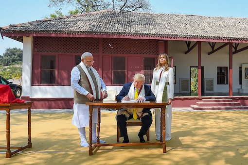 US President Donald Trump signs the visitor's book as Prime Minister Narendra Modi and First Lady Melania Trump looks on, at Sabarmati Ashram, in Ahmedabad on Monday. (PTI)