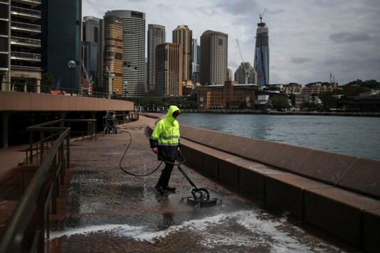 A worker cleans the mostly deserted waterfront area of the Sydney Opera House, in the wake of New South Wales implementing measures shutting down non-essential businesses and moving toward harsh penalties to enforce self-isolation as the spread of coronavirus disease (COVID-19). . REUTERS/Loren Elliott