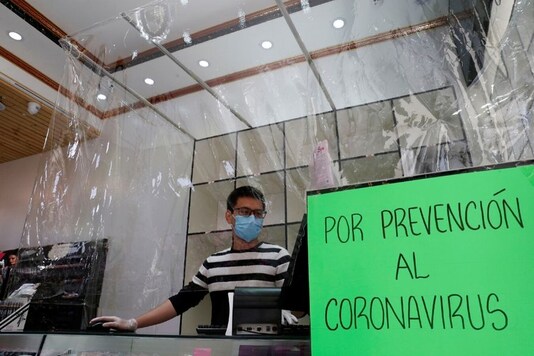 An employe of a store wears a face mask as he works behind a plastic curtain as a precaution against the spread of the coronavirus disease (COVID-19) in Vina del Mar, Chile March 14, 2020. REUTERS/Rodrigo Garrido
