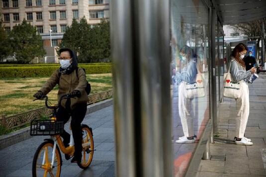 People wear face masks near a bus stop on a street following an outbreak of the coronavirus disease (COVID-19), in Beijing, China. (Reuters)