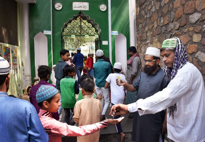  Volunteers pour sanitizers on the hands of devotees entering a mosque to prevent the spread of coronavirus, at Nizamuddin area in New Delhi. (Image: PTI)