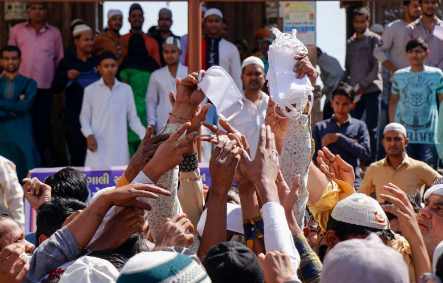  Muslims distribute face masks in the wake of coronavirus pandemic outside a mosque after Friday prayers in Ahmedabad. (Image: PTI)