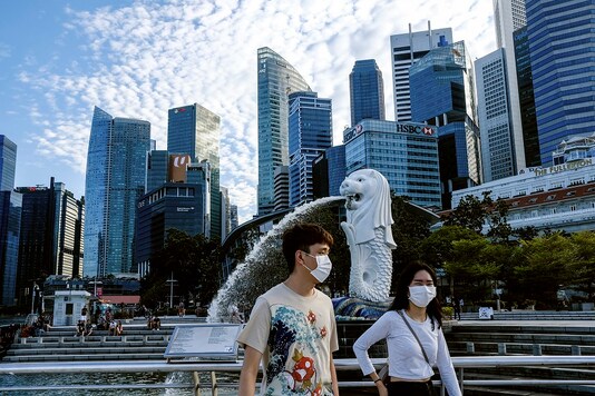 A couple wearing face masks walk past the Merlion statue in Singapore. (AP Photo)