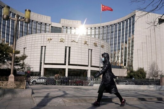 Representative image: A woman wearing a mask walks past the headquarters of the People's Bank of China, the central bank, in Beijing, China. (REUTERS/Jason Lee)