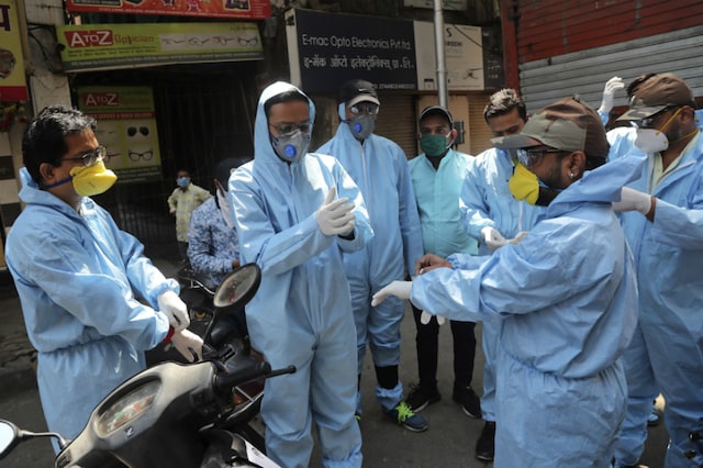 Members of a voluntary organisation wear protective gear before distributing food to people in Mumbai on March 29, 2020. (AP Photo/Rafiq Maqbool)