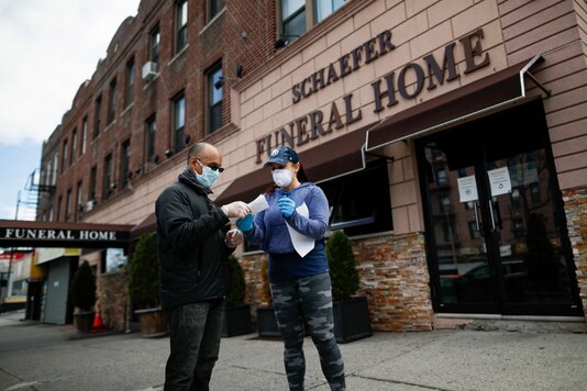 Employee Gina Hansen hands documentation to a client outside Daniel J. Schaefer Funeral Home in the Brooklyn borough of New York. (Image: AP)