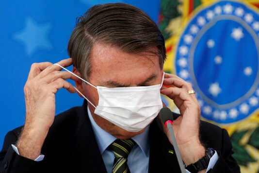 Brazil's Jair Bolsonaro adjusts his protective face mask during a news conference to announce measures to curb the spread of the coronavirus disease (COVID-19) in Brasilia, Brazil March 18, 2020. (REUTERS/Adriano Machado/File Photo)