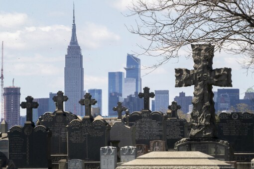 The Empire State building and the Manhattan skyline are seen behind the tombstones at Calvary Cemetery, on April 11, 2020, in the Maspeth neighborhood of the Queens borough of New York. (AP Photo/Mary Altaffer)