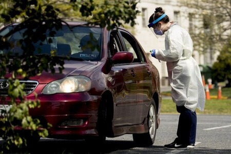 A medical worker tests a young man for COVID-19 at a Children's National Hospital drive-through (drive-in) coronavirus testing site at Trinity University, Thursday, April 16, 2020, in Washington. (AP Photo/Andrew Harnik)