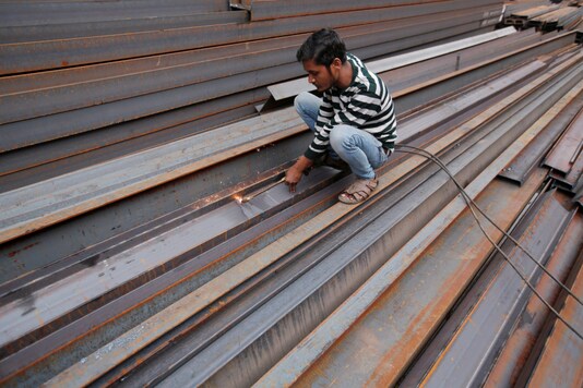 FILE PHOTO: A worker cuts iron rods outside a workshop at an iron and steel market in an industrial area in New Delhi, India, December 12, 2017. REUTERS/Adnan Abidi/File Photo