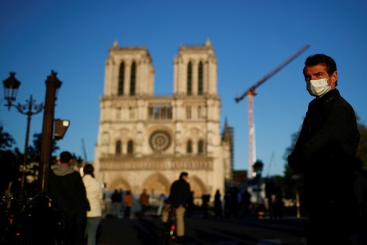 A man wearing a face mask listens to the Notre-Dame de Paris Cathedral's great bell ringing, as a mark of the building's resilience one year after a devastating fire, during the coronavirus disease (COVID-19) outbreak, France. (Reuters)