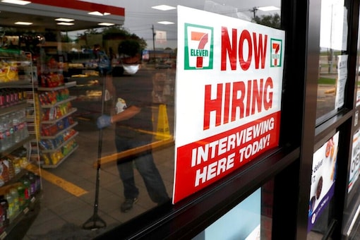 A sign on the window at a 7-Eleven store reads, "Now Hiring," as an employee inside the store wears a mask and gloves while mopping the floor amid the coronavirus health crisis in Dallas, Wednesday, April 22, 2020. (AP Photo/Tony Gutierrez)