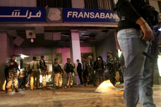 Lebanese security forces inspect the entrance of a Fransabank branch in Lebanon's southern city of Sidon on April 25, 2020, after unknown assailants targeted the bank entrance with an explosive device. (AFP)