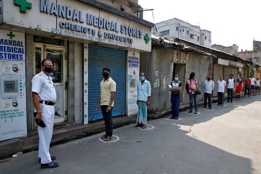 People look on as they stand in circles drawn to maintain safe distance while waiting to buy medicine. REUTERS