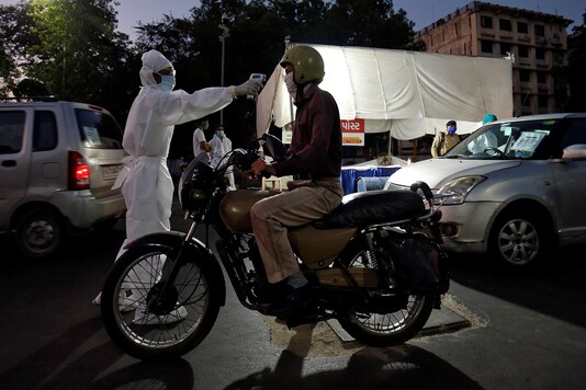 A health worker uses an infrared thermometer to measure the temperature of a motorcyclist on a road during a nationwide lockdown to slow the spreading of the coronavirus. (REUTERS)