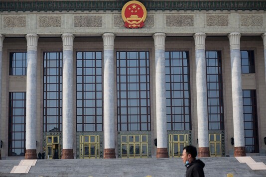 FILE PHOTO: A man with a face mask walks past the Great Hall of the People, as the country is hit by an outbreak of the novel coronavirus, in Beijing, China February 19, 2020. REUTERS/Tingshu Wang/File Photo