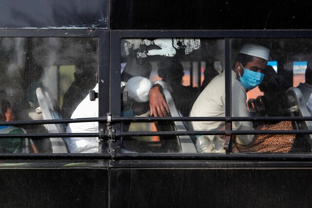 Men wearing protective masks sit inside a bus that will take them to a quarantine facility, amid concerns about the spread of coronavirus disease (COVID-19), in Nizamuddin area of New Delhi, India, March 31, 2020. REUTERS/Adnan Abidi - RC2SUF9AFGS6