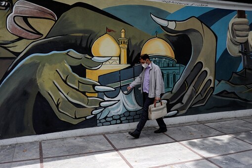 A man wearing a protective face mask walks past a Palestine mural on the wall following the outbreak of the coronavirus disease (COVID-19), in Tehran, Iran. (West Asia News Agency)/Ali Khara via REUTERS 