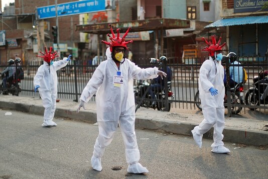 Artists wearing coronavirus-shaped helmets and protective suits walk on a street as they request people to stay at home during an extended lockdown in New Delhi. (Reuters)