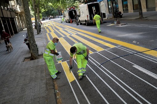Workerd paint lines on the street to expand a sidewalk for pedestrians to keep a social distance between them, as the spread of the coronavirus disease (COVID-19) continues in Barcelona, Spain. (Reuters)