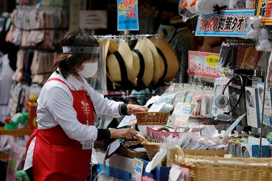 An employee of a retail store wearing a protective face mask and a face mask is seen outside of the store in Tokyo, Japan. (Reuters)