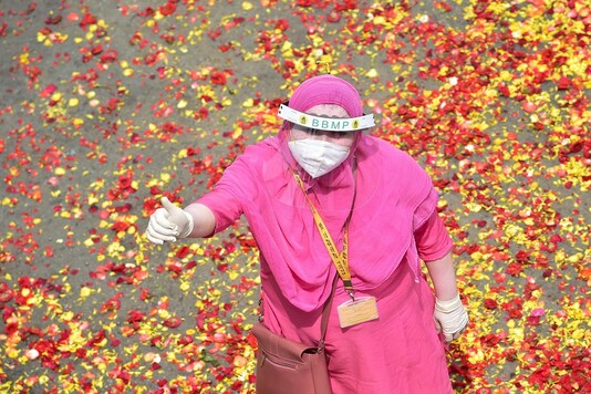 An ASHA worker looks up as she is showered with flower petals at a felicitation event for her service in the wake of novel coronavirus pandemic in Bengaluru. (PTI Photo)