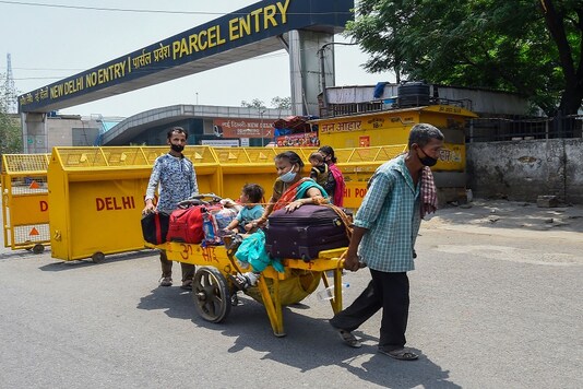 A physically challenged passenger is carried along with her luggage by a porter after arriving at New Delhi Railway Station from West Bengal on Thursday. (PTI Photo)
