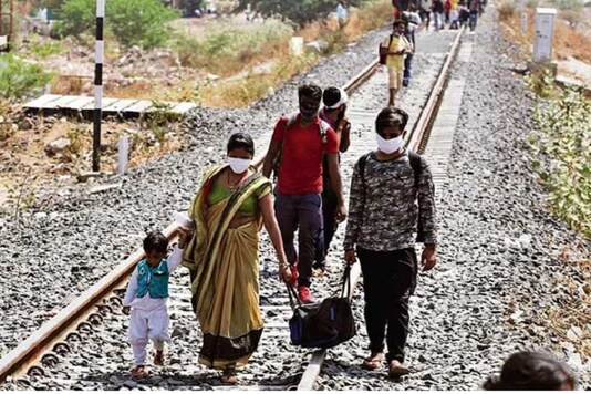 Migrant workers from other states desperate to return to their homes walk through rail tracks towards a train station in Ahmedabad on May 11, 2020. (Photo: AP)