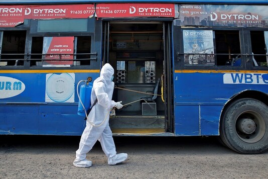 A man wearing a protective gear sprays disinfectant on a bus before passengers board, after the state government resumed public bus service on limited routes after nearly seven-week lockdown to slow the spreading of the coronavirus disease. (Reuters)